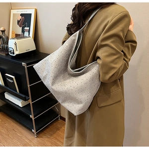 Détail d'un sac cabas argenté brillant avec strass, forme hobo souple et bandoulière large