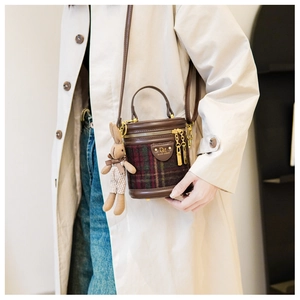Détail d'un mini sac cylindre vintage à carreaux avec breloque lapin en peluche et chaîne