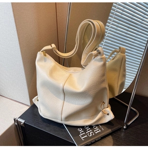 Detail of creamy white hobo bag showing soft leather texture and golden metal rings