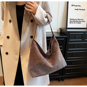 Detalle de un bolso hobo marrón oscuro con pedrería plateada usado por una modelo