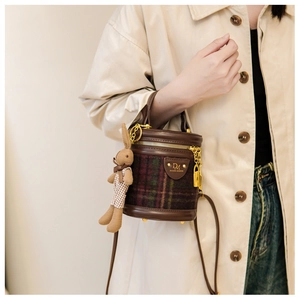 Détail du sac seau à carreaux vintage avec garniture en cuir brun et breloque lapin