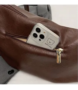 Detail of a dark brown pebble leather bag side pocket with gold zipper and smartphone storage