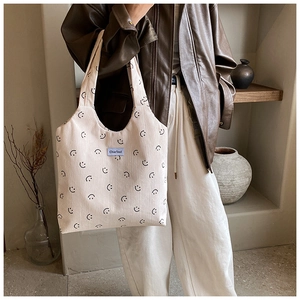 Détail du sac fourre-tout en velours côtelé avec motifs smiley et étiquette bleue
