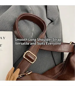 Detail of adjustable long shoulder strap and golden hardware on dark brown bag