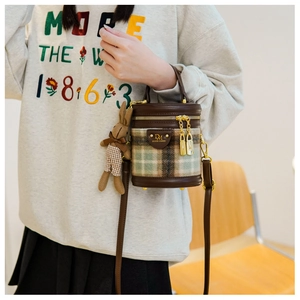 Détail du sac seau en tweed à carreaux avec bordure en cuir et pendentif lapin