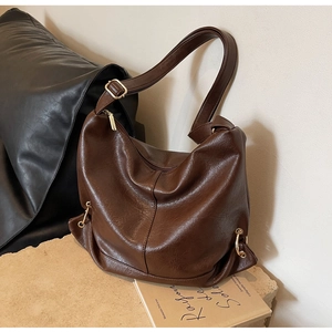 Detail of soft brown pebble leather texture and gold metal ring on large hobo bag