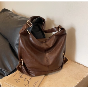Detail of dark brown leather texture and gold hardware on large hobo tote bag