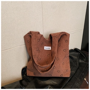 Détail d'un sac cabas en velours côtelé marron avec texture côtelée et motif smiley