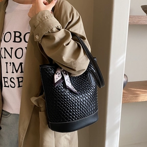 Large black woven leather bucket bag with white stitching and decorative silk scarf