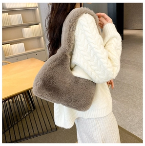 Dettaglio della borsa a mezzaluna in pelliccia sintetica talpa con maglione bianco