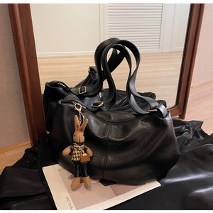 Detail of black faux leather tote bag with wide straps and cute rabbit charm pendant