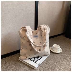 Détail du sac cabas en velours côtelé beige avec motif sourire et étiquette de marque