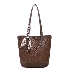 Brown woven leather bucket bag with white stitching and decorative silk scarf detail