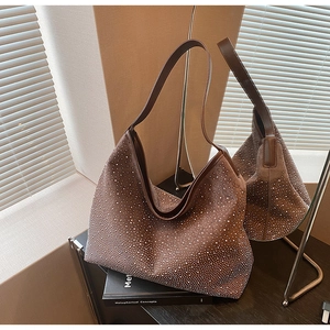Dettaglio laterale di borsa hobo in pelle scamosciata marrone con strass e tracolla