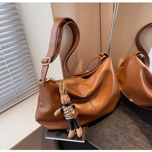 Detail of brown pleated hobo bag with adjustable strap and cute rabbit pendant