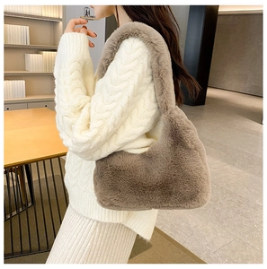 Dettaglio della borsa a mezzaluna in peluche marrone con completo in maglia beige