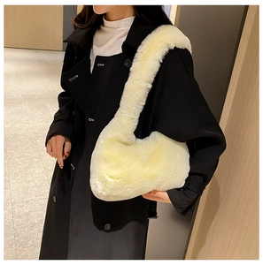 Vista laterale del sacchetto a mezzaluna in peluche bianco panna su un cappotto nero