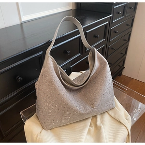 Dettaglio della borsa hobo con strass luccicanti e tracolla larga su mobile vintage