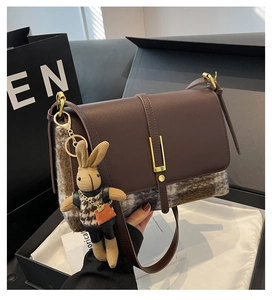 Detail of vintage crossbody bag with brown leather, plaid tweed, and rabbit charm