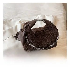 Détail de la texture peluche marron et de la chaîne en métal argenté du sac à main