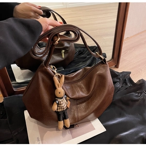 Detail of dark brown leather crescent bag with adjustable strap and rabbit charm