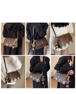 Detail view of vintage plaid crossbody bag with metal buckle and cute rabbit charm accent