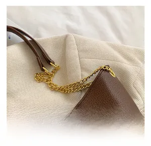 Détail de sac seau en cuir PU marron grainé avec une bandoulière en chaîne dorée chic