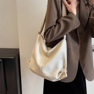 Minimalist beige PU leather hobo tote bag with gold ring detail worn by a model