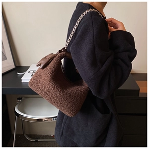 Détail d'un sac bandoulière en laine d'agneau pelucheuse avec chaîne argentée et nœud en cuir