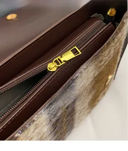 Detail of the golden metal zipper pull on a fluffy faux fur crossbody bag for women