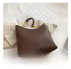 Vue détaillée du sac cabas en cuir grainé marron avec chaîne dorée et plaque logo