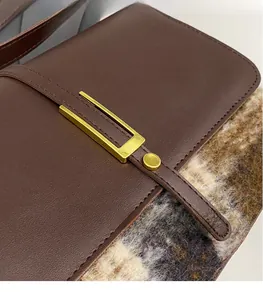Detail of vintage brown leather bag with golden U-shaped metal buckle and neat stitching