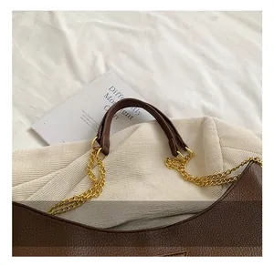 Détail du cuir grainé marron foncé avec chaîne dorée et poignée sur le sac à main