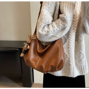 Detailed close-up of a caramel brown pleated hobo bag with a cute plush bunny charm