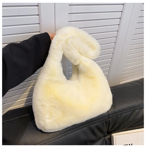Dettaglio della borsa a mezzaluna in pelliccia sintetica crema con texture soffice e manico