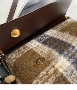 Detail of vintage leather bag showing plaid wool lining and golden magnetic clasp