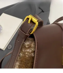 Detail of golden square metal buckle and brown leather texture on stylish handbag