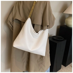 Détail d'un sac hobo en cuir litchi blanc avec bandoulière chaîne dorée et patch