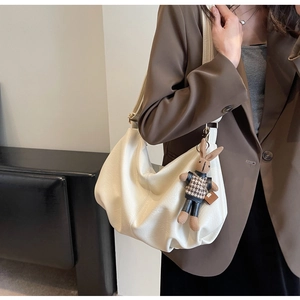Detail of cream white pleated dumpling bag featuring a cute rabbit charm accessory