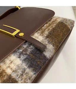 Close-up of retro plaid wool fabric and premium brown leather strap with golden buckle