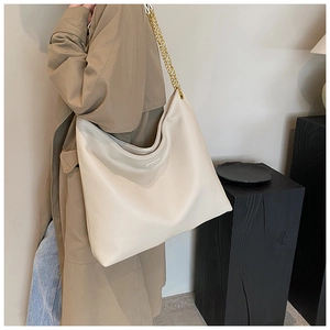 Détail du sac cabas en cuir crème avec bandoulière chaîne dorée et triangle métallique