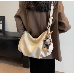 Detail of soft pleated cream croissant bag with a cute knitted bunny charm accessory