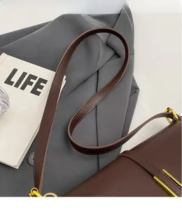 Close-up of slim brown leather shoulder strap and gold hardware on a retro handbag