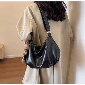 Detail of black large capacity hobo bag featuring pleated leather and a cute bunny pendant
