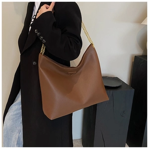 Détail du grand sac seau marron en similicuir avec chaîne dorée et plaque triangulaire