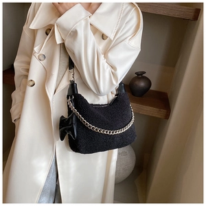 Détail du sac hobo en polaire noire avec chaîne argentée et accessoire de nœud en cuir