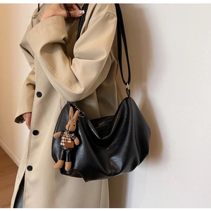 Detail of black pleated PU leather bag with cute plush rabbit pendant and long strap