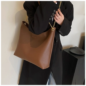 Détail du sac cabas en cuir marron foncé avec texture grainée et chaîne dorée