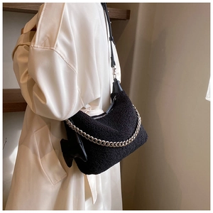 Détail de la texture en peluche noire avec chaîne argentée sur un sac à bandoulière doux