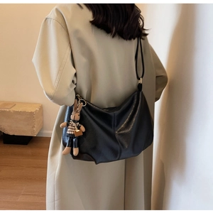 Detail of a black leather hobo bag with a soft pleated texture and a cute rabbit pendant